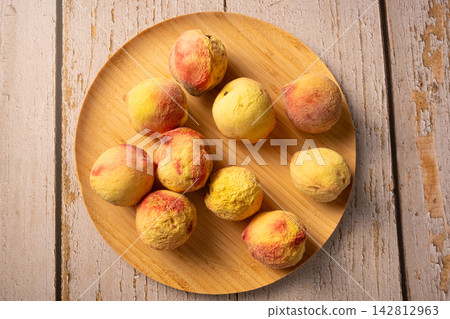 Old peaches, some old peaches in a rustic bowl on a rustic wooden table, selective focus. 142812963