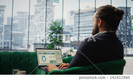 Goals oriented businessman in high end corporate office plans a strategy to ensure company future, reviewing market research and tracking expenses. Obtaining corporate achievement. Camera A. Goals oriented businessman in high end corporate office plans a strategy to ensure company future, reviewing market research and tracking expenses. Obtaining corporate achievement. Camera A. 142812980