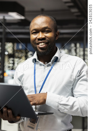 Doing research, laptop and portrait of cheerful businessman standing in office planning investment project. Working, notebook and jolly African american man increasing company profit 142813035