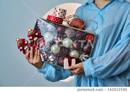 Woman holding box of christmas decorations and gift Woman holding box of christmas decorations and gift 142813590