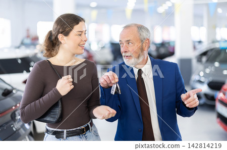 Elderly car dealer gives a woman a set of keys to a new car Elderly car dealer gives a woman a set of keys to a new car 142814219