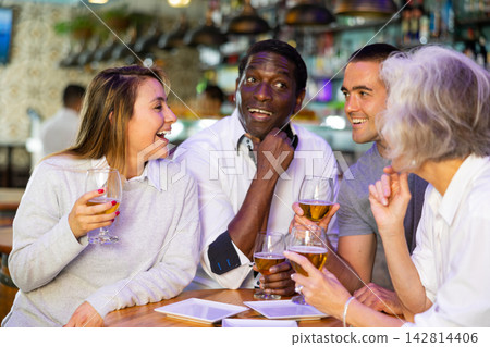 Happy diverse people drinking beer and eating tapas while spending time together in a bar Happy diverse people drinking beer and eating tapas while spending time together in a bar 142814406