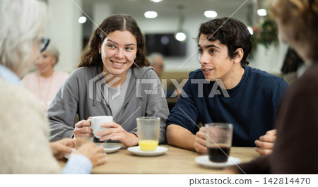 Young couple chatting with family in cafe Young couple chatting with family in cafe 142814470