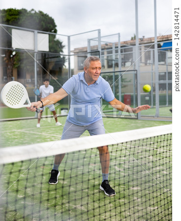 Emotional mature man playing paddle tennis outdoors 142814471