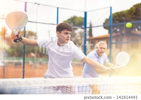 Two male tennis partners playing padel game on cort 142814491