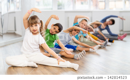 Little school age children learn to do dance moves on the floor in choreography studio Little school age children learn to do dance moves on the floor in choreography studio 142814523