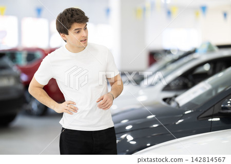 Young man choosing car at auto dealership Young man choosing car at auto dealership 142814567