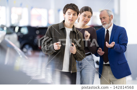 Elderly car dealership salesman offers to buy car to young couple Elderly car dealership salesman offers to buy car to young couple 142814568