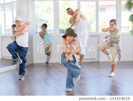 Young boys and girls performing hip hop at group dance class in choreographic studio Young boys and girls performing hip hop at group dance class in choreographic studio 142814610
