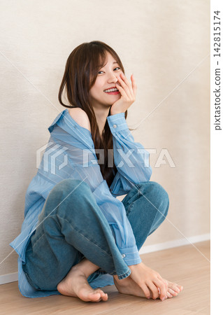 一位女士微笑著坐著,穿著藍色襯衫和牛仔褲,休閒時尚,令人耳目一新。 一位女士微笑著坐著,穿著藍色襯衫和牛仔褲,休閒時尚,令人耳目一新。 142815174