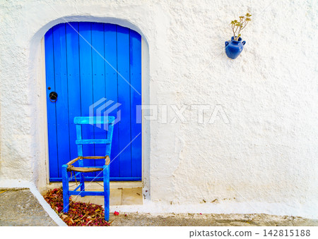 Blue door and chair against white wall Cretan village Crete Greece Blue door and chair against white wall Cretan village Crete Greece 142815188