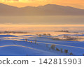 Biei: Snow-covered hills enveloped in the morning glow and mist. 142815903