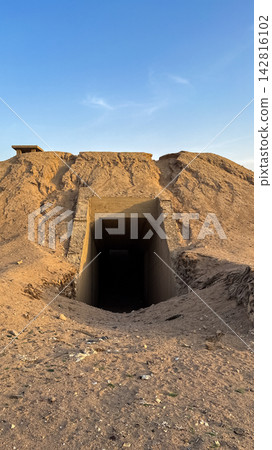 Concrete tunnel entrance leads into a dark sandy mound Concrete tunnel entrance leads into a dark sandy mound 142816102