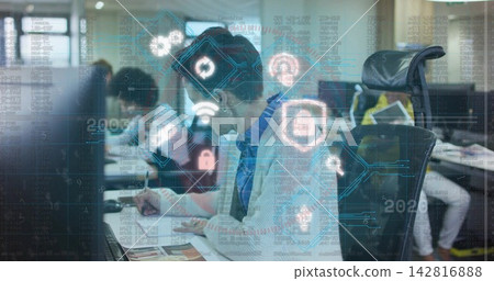Writing man wearing sweater, referencing documents near laptop in office with security UI Writing man wearing sweater, referencing documents near laptop in office with security UI 142816888