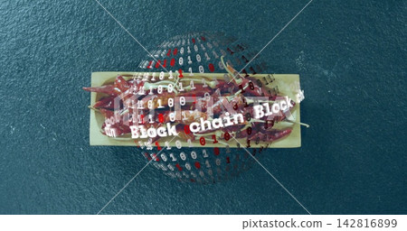 Displaying wood tray holding red chili peppers on studio table, binary globe showing Block chain Displaying wood tray holding red chili peppers on studio table, binary globe showing Block chain 142816899