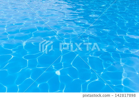 Clear blue water surface of a swimming pool reflects sunlight, featuring gentle ripples and patterns that create a serene aquatic environment Clear blue water surface of a swimming pool reflects sunlight, featuring gentle ripples and patterns that create a serene aquatic environment 142817898