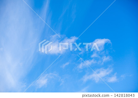 Clear blue sky featuring white clouds scattered throughout, with wispy formations adding texture to the serene daytime scene Clear blue sky featuring white clouds scattered throughout, with wispy formations adding texture to the serene daytime scene 142818043