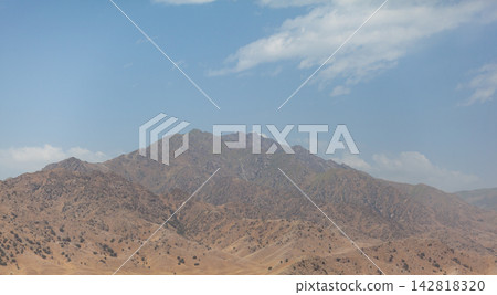 Mountainous region features rocky terrain and sparse vegetation beneath a clear blue sky, highlighting the natural landscape and geological formations Mountainous region features rocky terrain and sparse vegetation beneath a clear blue sky, highlighting the natural landscape and geological formations 142818320