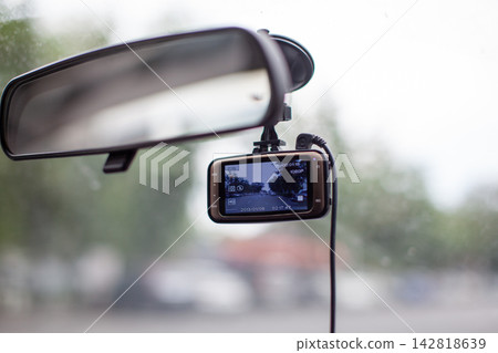 Dashboard camera is attached to the rearview mirror, recording the road ahead through the windshield inside a vehicle Dashboard camera is attached to the rearview mirror, recording the road ahead through the windshield inside a vehicle 142818639