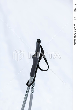 Close-up view of a black ski pole grip featuring a strap, set against a soft, white snowy background, emphasizing winter sports gear Close-up view of a black ski pole grip featuring a strap, set against a soft, white snowy background, emphasizing winter sports gear 142818707