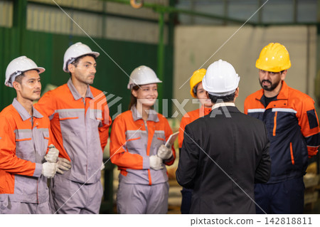Chief engineer leading team meeting with factory workers. Factory Teamwork in workplace collaboration in manufacturing environment. Chief engineer leading team meeting with factory workers. Factory Teamwork in workplace collaboration in manufacturing environment. 142818811