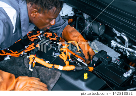 Professional Electric Vehicle Mechanic Working High Voltage Electricity Lines Wiring in Engine Bay EV Garage Professional Electric Vehicle Mechanic Working High Voltage Electricity Lines Wiring in Engine Bay EV Garage 142818851