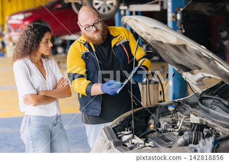 Mechanic Explains Car Repairs in Garage to Attentive Customer. Mechanic Explains Car Repairs in Garage to Attentive Customer. 142818856