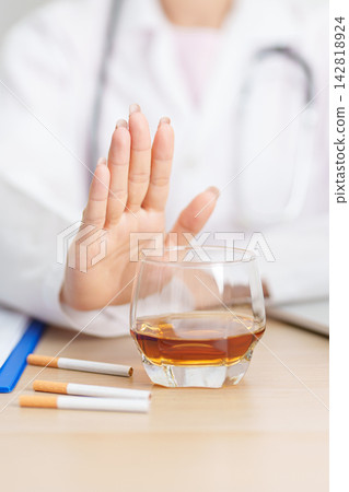 doctor hand making stop sign to refuse whiskey and breaking cigarette, quit smoking and drinking for healthy liver and lung, World No Tobacco and No Alcohol Day and stop alcohol addiction concept doctor hand making stop sign to refuse whiskey and breaking cigarette, quit smoking and drinking for healthy liver and lung, World No Tobacco and No Alcohol Day and stop alcohol addiction concept 142818924