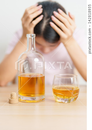 Stressed woman drinking whisky alone with problem. Exhausted drunk man looking stressed and sleepy. Alcohol addiction, Alcoholism, emotional distress and mental health concept Stressed woman drinking whisky alone with problem. Exhausted drunk man looking stressed and sleepy. Alcohol addiction, Alcoholism, emotional distress and mental health concept 142818935