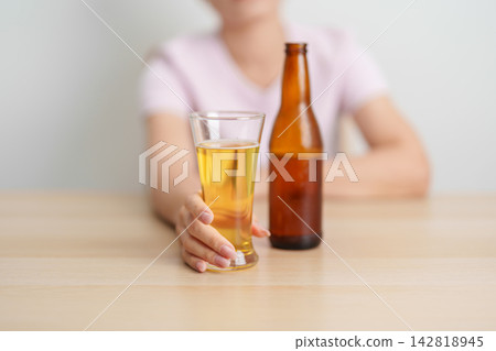 woman with glass of Beer on table, suffering from alcohol addiction and alcoholism concept. depicting emotional distress, depression, substance abuse problem, unhealthy lifestyle and mental health woman with glass of Beer on table, suffering from alcohol addiction and alcoholism concept. depicting emotional distress, depression, substance abuse problem, unhealthy lifestyle and mental health 142818945