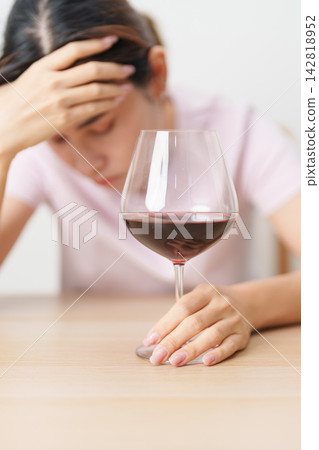 Stressed woman drinking Wine alone with problem. Exhausted drunk woman looking stressed and sleepy. Alcohol addiction, Alcoholism, emotional distress and mental health concept Stressed woman drinking Wine alone with problem. Exhausted drunk woman looking stressed and sleepy. Alcohol addiction, Alcoholism, emotional distress and mental health concept 142818952