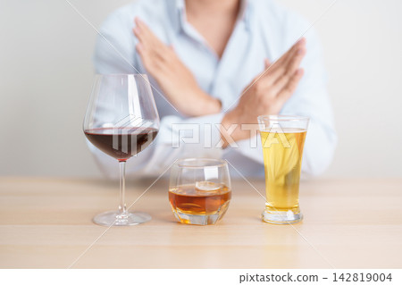 man stop hand gesture to refuse a glass of wine, beer, whiskey or cognac on table. say no to alcohol drink, stop alcoholism addiction, Responsibility, reject a drink before drive and quit booze 142819004