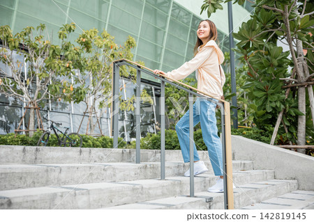 Close-up of a woman's legs in sneakers conquering the city stairway. Each step signifies determination, progress, and her unwavering pursuit of success and achievement. step up Close-up of a woman's legs in sneakers conquering the city stairway. Each step signifies determination, progress, and her unwavering pursuit of success and achievement. step up 142819145