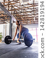 Asian female wearing leggings, preparing deadlift with Olympic barbell on rubber floor at gym 142819194