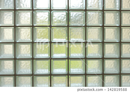 A wall of neatly arranged transparent glass blocks: geometric patterns and a light-filled background. A wall of neatly arranged transparent glass blocks: geometric patterns and a light-filled background. 142819588