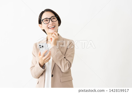 一位身穿西裝、戴著眼鏡的女士正在使用智慧型手機。 一位身穿西裝、戴著眼鏡的女士正在使用智慧型手機。 142819917