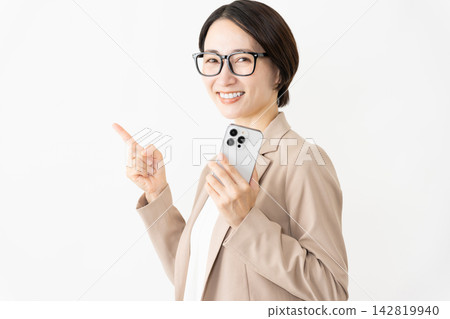 A woman in a suit and glasses using a smartphone. A woman in a suit and glasses using a smartphone. 142819940