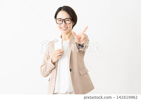 A woman in a suit and glasses using a smartphone. 142819962