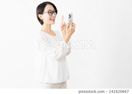 一位戴著眼鏡、身穿T恤的女士正在使用智慧型手機——生活方式圖片 一位戴著眼鏡、身穿T恤的女士正在使用智慧型手機——生活方式圖片 142820667