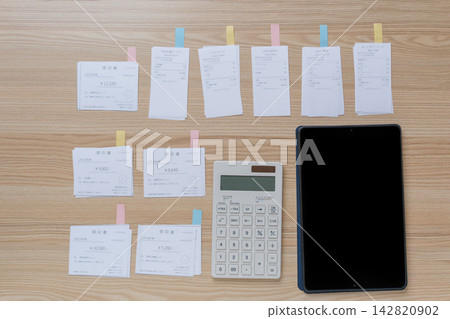 An image of household budget and expense management using a calculator and tablet to organize receipts and invoices. An image of household budget and expense management using a calculator and tablet to organize receipts and invoices. 142820902