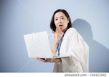 一位女上班族看著她的筆記型電腦，臉上露出驚訝、震驚和憂慮的神情，可能是因為工作上的問題、錯誤或麻煩。 142821082