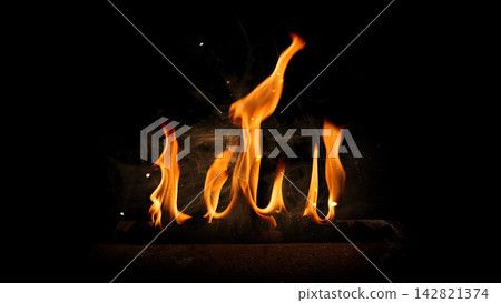Bright orange fire flames rising against a pitch black background with subtle smoke and embers. Fire background Bright orange fire flames rising against a pitch black background with subtle smoke and embers. Fire background 142821374
