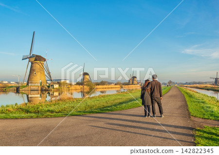 Dutch Windmill landscape at Kinderdijk Village Netherlands with love couple walking Dutch Windmill landscape at Kinderdijk Village Netherlands with love couple walking 142822345