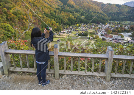 Shirakawago village Gifu Japan woman tourist taking photo at Gassho house in autumn season Shirakawago village Gifu Japan woman tourist taking photo at Gassho house in autumn season 142822384