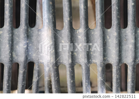 Closeup of an old metal grate with vertical openings creates a geometric industrial pattern showing construction hardware and functional structural design. Closeup of an old metal grate with vertical openings creates a geometric industrial pattern showing construction hardware and functional structural design. 142822511