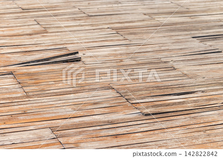 Sunlit weathered wooden deck planks show warped, aged boards Sunlit weathered wooden deck planks show warped, aged boards 142822842