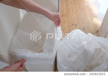 Replacing the trash bag in the bathroom trash can. Replacing the trash bag in the bathroom trash can. 142823831