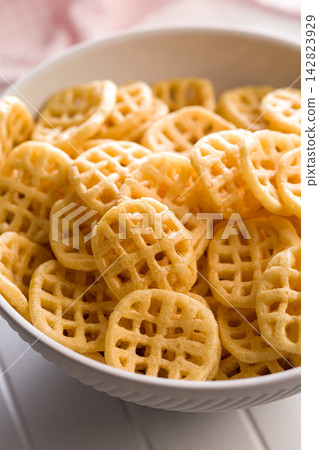 Bowl Of Crispy Waffle Potato Chips Snack Food In A White Bowl For Parties And Snacking Bowl Of Crispy Waffle Potato Chips Snack Food In A White Bowl For Parties And Snacking 142823929