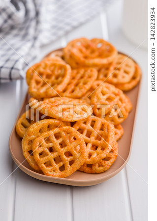 Seasoned Waffle Potato Chips Piled On Plate. Closeup Of Crispy Savory Snack Seasoned Waffle Potato Chips Piled On Plate. Closeup Of Crispy Savory Snack 142823934