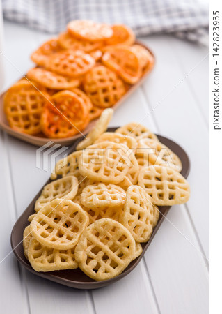 Two Bowls of Waffle Fries and Potato Snacks. Spicy and Classic Seasoned Chips on Table Two Bowls of Waffle Fries and Potato Snacks. Spicy and Classic Seasoned Chips on Table 142823935